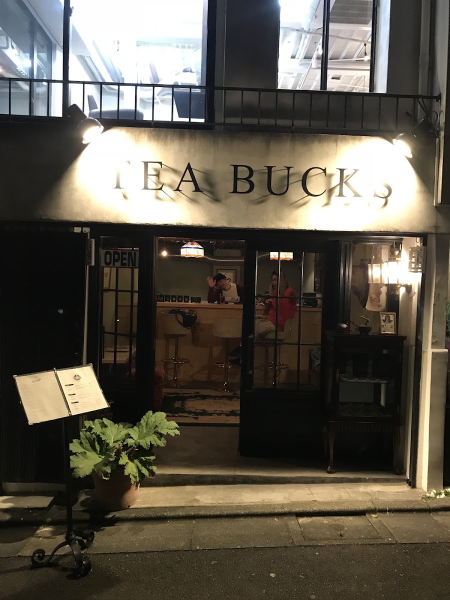 夜の店先。「TEA BUCKS」の文字と、明かりのついた窓。
